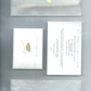 Set of stationery items that is included in the manifest ritual candle set including a card with a gold cloud, a ritual card and an envelope on a grey background.