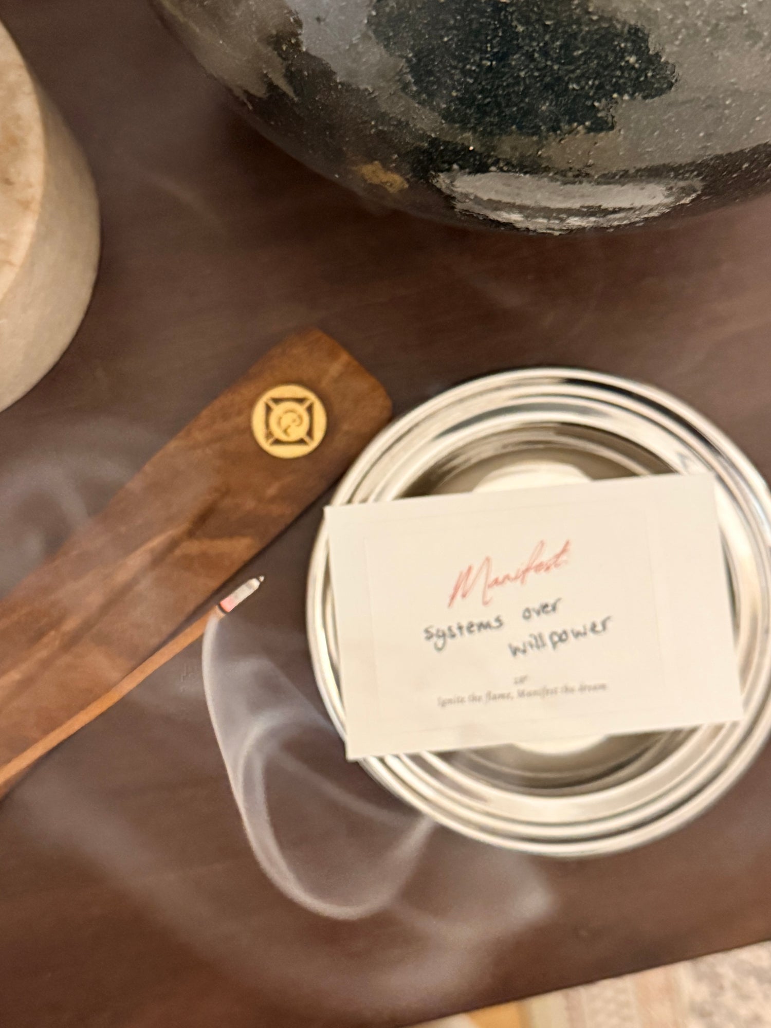 Incense stick and container with a manifest label on a wooden surface, written on the label- systems over willpower