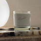 Candle in a glass container with a label on a marble surface
